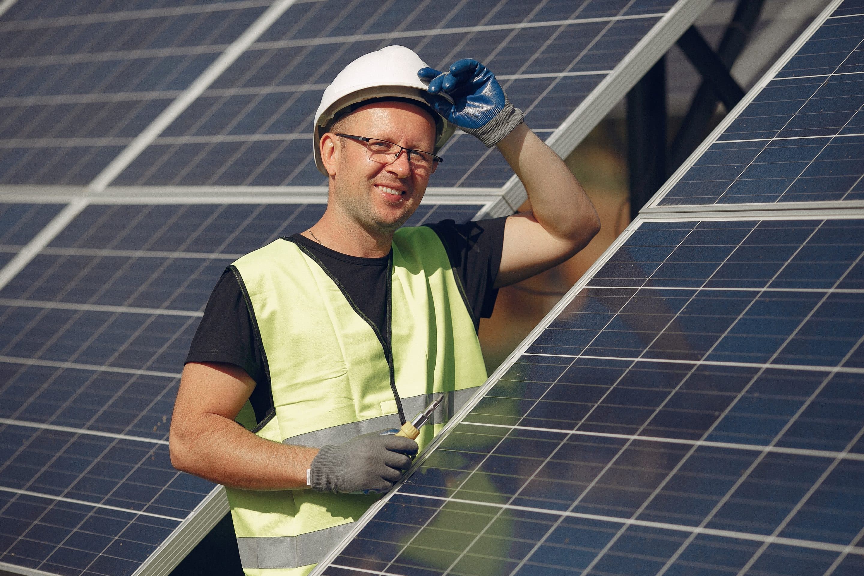 Man in a white helmet near a solar panel